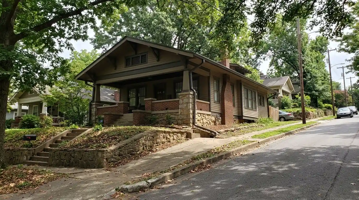 Craftsman bungalow with wide eaves and new one-piece aluminum gutters on a tree-shaded hillside street in Park Hill, North Little Rock Arkansas